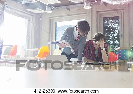 Creative businessmen reviewing document edits in sunny office View Large Photo Image Stock Image - Creative businessmen reviewing document edits in sunny office. Fotosearch