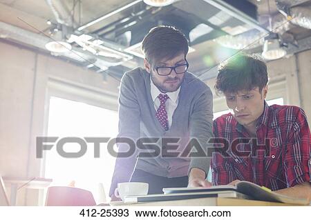 Creative businessmen reviewing document edits in sunny office View Large Photo Image Stock Image - Creative businessmen reviewing document edits in sunny office. Fotosearch