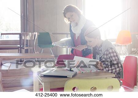 Creative businesswomen reviewing document edits in sunny office View Large Photo Image Stock Image - Creative businesswomen reviewing document edits in sunny office. Fotosearch