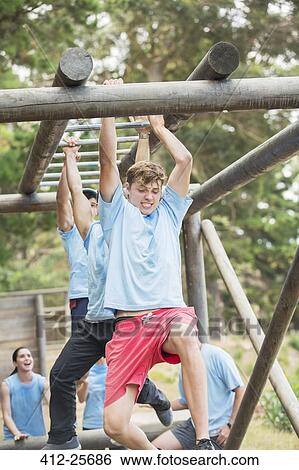 Determined man crossing monkey bars on boot camp obstacle course View Large Photo Image Stock Photograph - Determined man crossing monkey bars on boot camp obstacle course. Fotosearch
