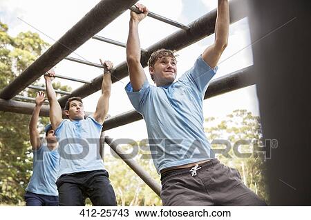 Determined men crossing monkey bars on boot camp obstacle course View Large Photo Image Stock Image - Determined men crossing monkey bars on boot camp obstacle course. Fotosearch