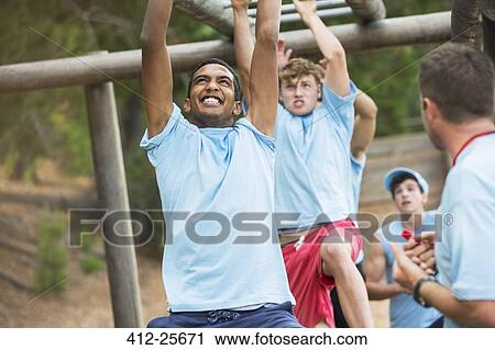 Determined men swinging on monkey bars on boot camp obstacle course View Large Photo Image Stock Image - Determined men swinging on monkey bars on boot camp obstacle course. Fotosearch