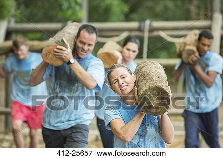 Determined people running with logs on boot camp obstacle course View Large Photo Image Stock Photo - Determined people running with logs on boot camp obstacle course. Fotosearch