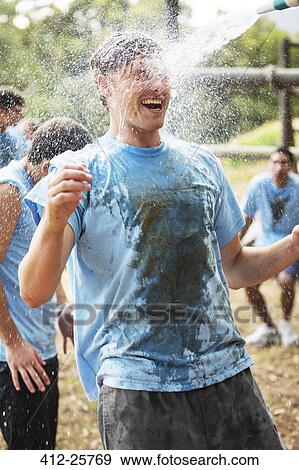 Enthusiastic man enjoying water hose spray on boot camp obstacle course View Large Photo Image Stock Photo - Enthusiastic man enjoying water hose spray on boot camp obstacle course. Fotosearch