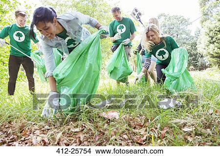 Environmentalist volunteers picking up trash in field View Large Photo Image Picture - Environmentalist volunteers picking up trash in field. Fotosearch