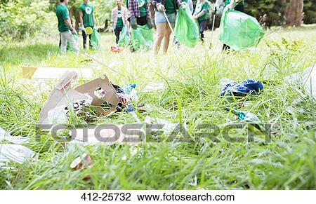 Environmentalist volunteers picking up trash in field View Large Photo Image Stock Image - Environmentalist volunteers picking up trash in field. Fotosearch