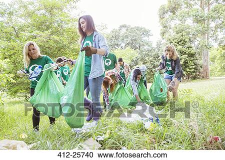 Environmentalist volunteers picking up trash in field View Large Photo Image Stock Image - Environmentalist volunteers picking up trash in field. Fotosearch
