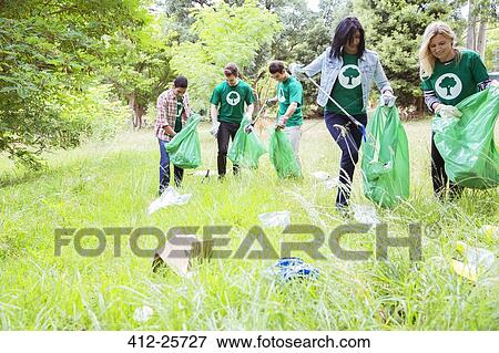Environmentalist volunteers picking up trash in field View Large Photo Image Stock Photo - Environmentalist volunteers picking up trash in field. Fotosearch