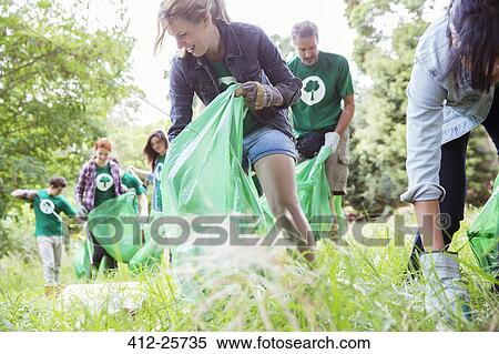 Environmentalist volunteers picking up trash in field View Large Photo Image Stock Photography - Environmentalist volunteers picking up trash in field. Fotosearch