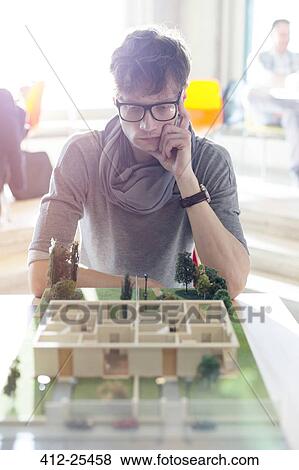 Focused architect viewing model in office View Large Photo Image Stock Photo - Focused architect viewing model in office. Fotosearch