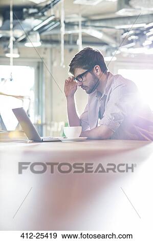 Focused businessman working at laptop View Large Photo Image Stock Photo - Focused businessman working at laptop. Fotosearch