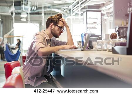 Focused businessman working at laptop in cafe View Large Photo Image Stock Photo - Focused businessman working at laptop in cafe. Fotosearch