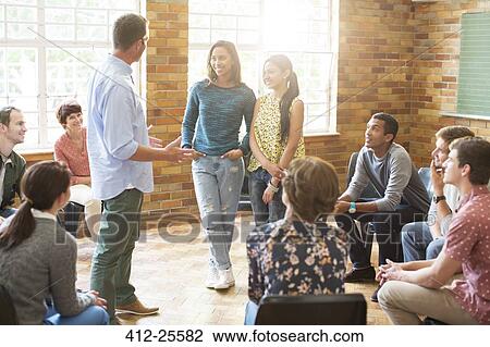 Stock Image - Man and women talking in group therapy session. Fotosearch