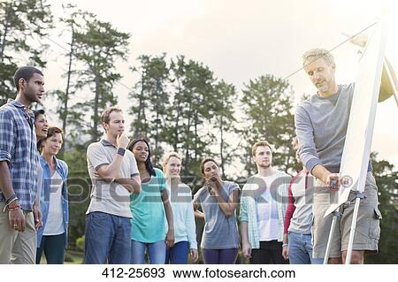 Man leading meeting at flipchart outdoors View Large Photo Image Stock Image - Man leading meeting at flipchart outdoors. Fotosearch