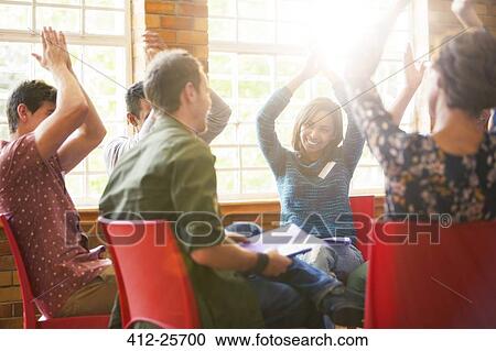 Stock Image - People clapping overhead in group therapy session. Fotosearch