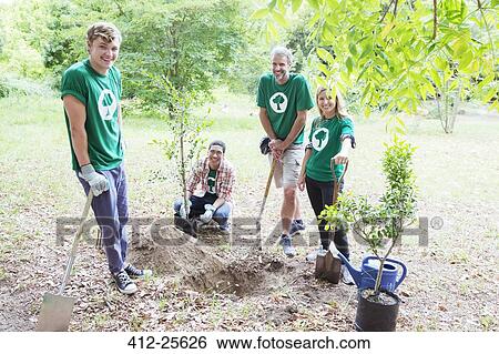 Stock Photograph - Portrait of confident environmentalist volunteers planting new tree. Fotosearch