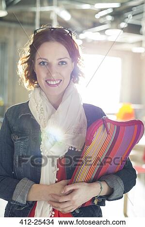Portrait of smiling casual businesswoman holding laptop case View Large Photo Image Picture - Portrait of smiling casual businesswoman holding laptop case. Fotosearch