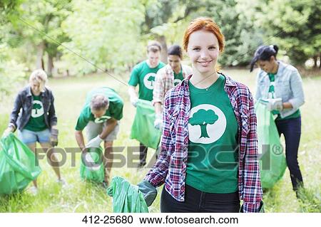 Stock Image - Portrait of smiling environmentalist volunteer picking up trash. Fotosearch