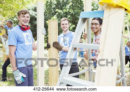 Portrait of smiling volunteers working at construction site View Large Photo Image Picture - Portrait of smiling volunteers working at construction site. Fotosearch
