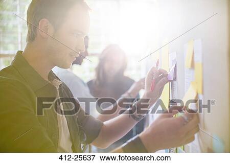 Stock Photo - Serious businessman reviewing adhesive notes on board. Fotosearch