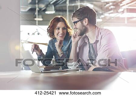 Smiling casual business people working at laptop View Large Photo Image Stock Image - Smiling casual business people working at laptop. Fotosearch