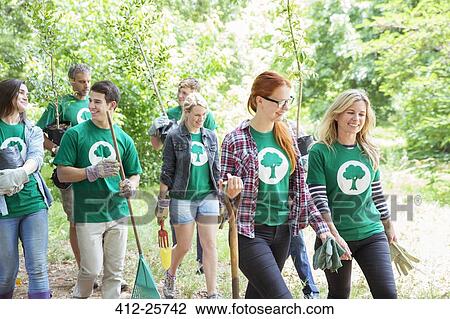Stock Image - Smiling environmentalist volunteers planting new tree. Fotosearch