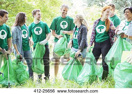 Stock Photograph - Smiling environmentalist volunteers picking up trash. Fotosearch