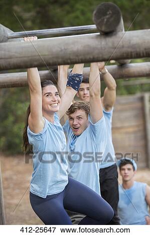 Smiling woman crossing monkey bars on boot camp obstacle course View Large Photo Image Stock Photo - Smiling woman crossing monkey bars on boot camp obstacle course. Fotosearch