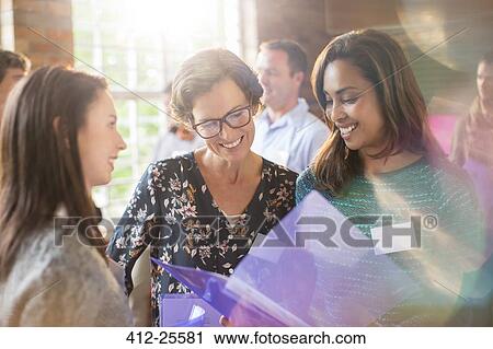 Smiling women looking at paperwork in community center View Large Photo Image Stock Image - Smiling women looking at paperwork in community center. Fotosearch