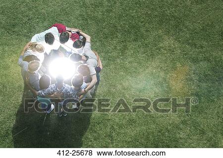 Team huddled in circle around glowing orb in field View Large Photo Image Stock Photo - Team huddled in circle around glowing orb in field. Fotosearch