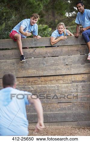 Teammates at wall cheering man on boot camp obstacle course View Large Photo Image Stock Image - Teammates at wall cheering man on boot camp obstacle course. Fotosearch
