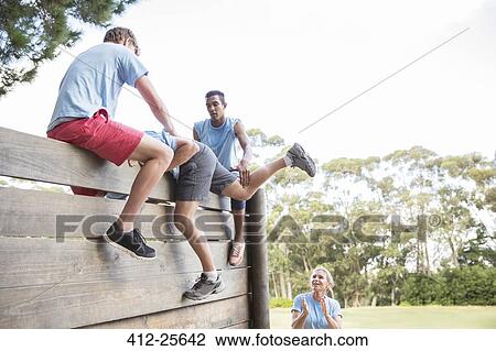 Teammates helping man over wall on boot camp obstacle course View Large Photo Image Stock Image - Teammates helping man over wall on boot camp obstacle course. Fotosearch