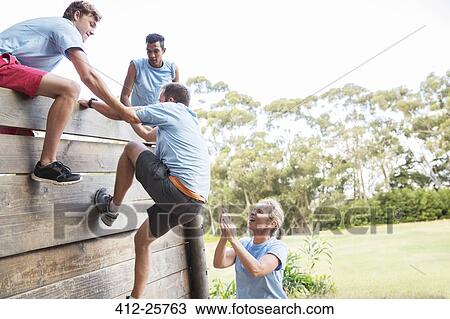 Teammates helping man over wall on boot camp obstacle course View Large Photo Image Stock Image - Teammates helping man over wall on boot camp obstacle course. Fotosearch