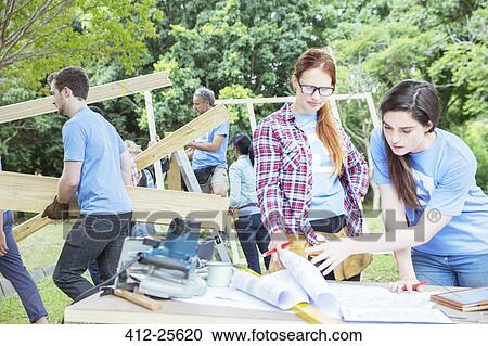 Volunteers reviewing blueprints at construction site View Large Photo Image Stock Image - Volunteers reviewing blueprints at construction site. Fotosearch