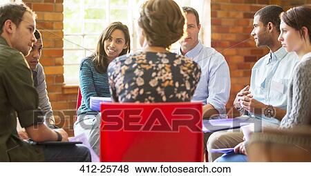 Stock Photo - Woman leading group therapy session. Fotosearch