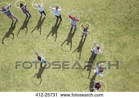Stock Image - Woman leading team with plastic hoops overhead. Fotosearch