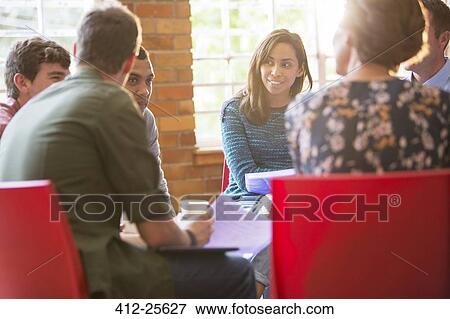 Stock Photo - Woman smiling and listening in group therapy session. Fotosearch