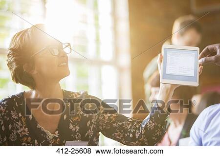 Stock Photo - Woman using digital tablet in sunny meeting. Fotosearch