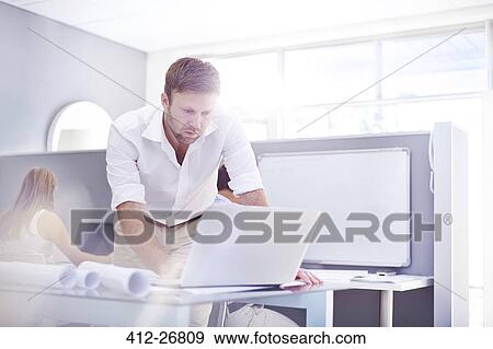 Stock Photo - Architect using laptop in sunny office. Fotosearch