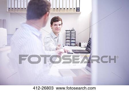 Architects discussing paperwork at desk in office View Large Photo Image Stock Image - Architects discussing paperwork at desk in office. Fotosearch
