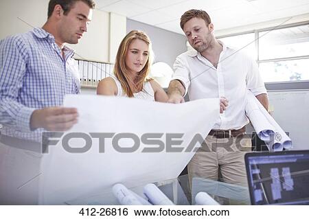 Architects reviewing blueprints in office View Large Photo Image Stock Photograph - Architects reviewing blueprints in office. Fotosearch
