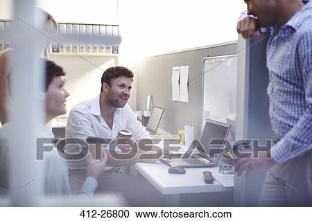 Stock Image - Architects talking and drinking coffee at laptop in office. Fotosearch