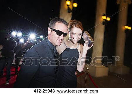 Stock Image - Bodyguard escorting smiling celebrity arriving at red carpet event. Fotosearch