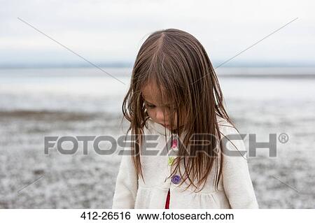 Stock Photograph - Brunette girl looking down at beach. Fotosearch