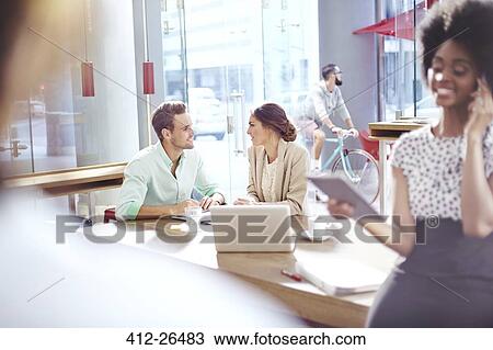 Stock Image - Business people talking face to face in cafe. Fotosearch