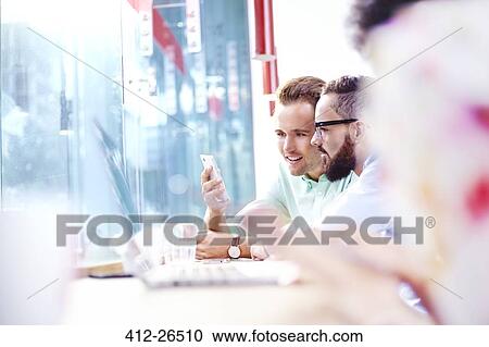 Stock Image - Businessmen texting with cell phone in cafe. Fotosearch