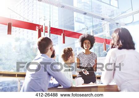 Businesswoman leading meeting in sunny office View Large Photo Image Stock Photo - Businesswoman leading meeting in sunny office. Fotosearch