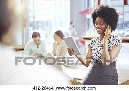Picture - Businesswoman talking and cell phone and using digital tablet. Fotosearch