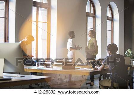 Stock Image - Businesswomen talking in office. Fotosearch