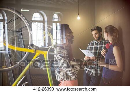 Casual business people discussing paperwork in office View Large Photo Image Stock Image - Casual business people discussing paperwork in office. Fotosearch